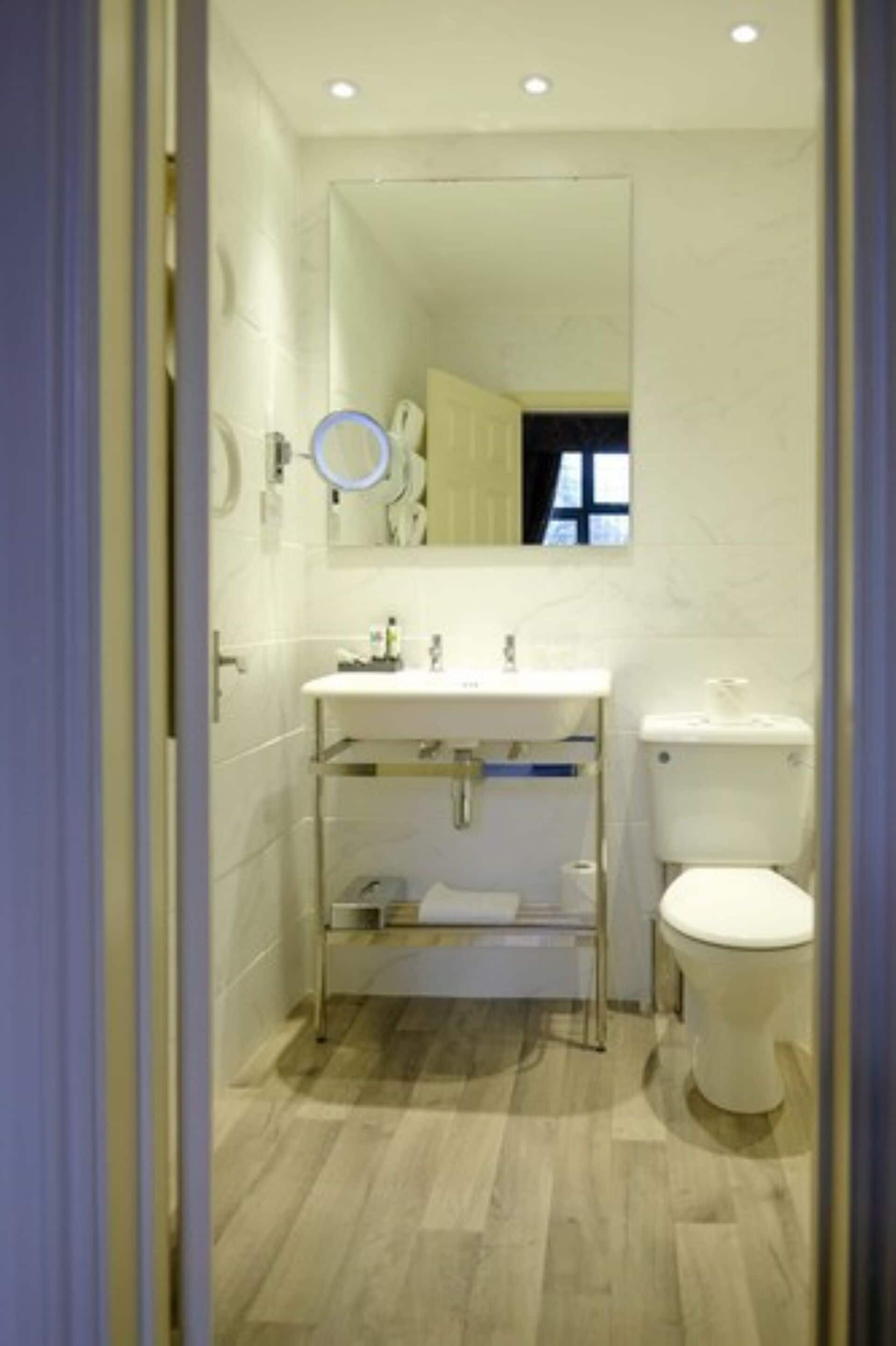 A modern bathroom with a white sink, mirror, and toilet.