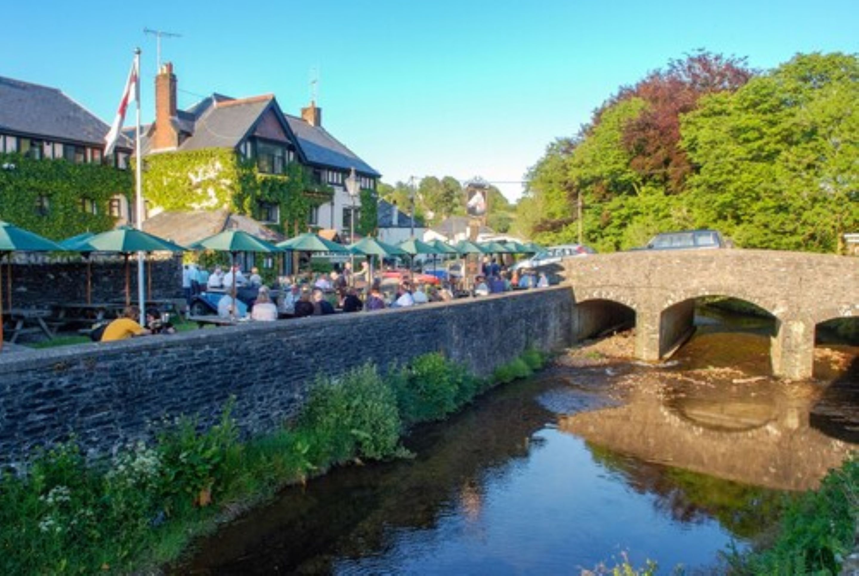 A riverside market with stone bridges and outdoor seating areas.