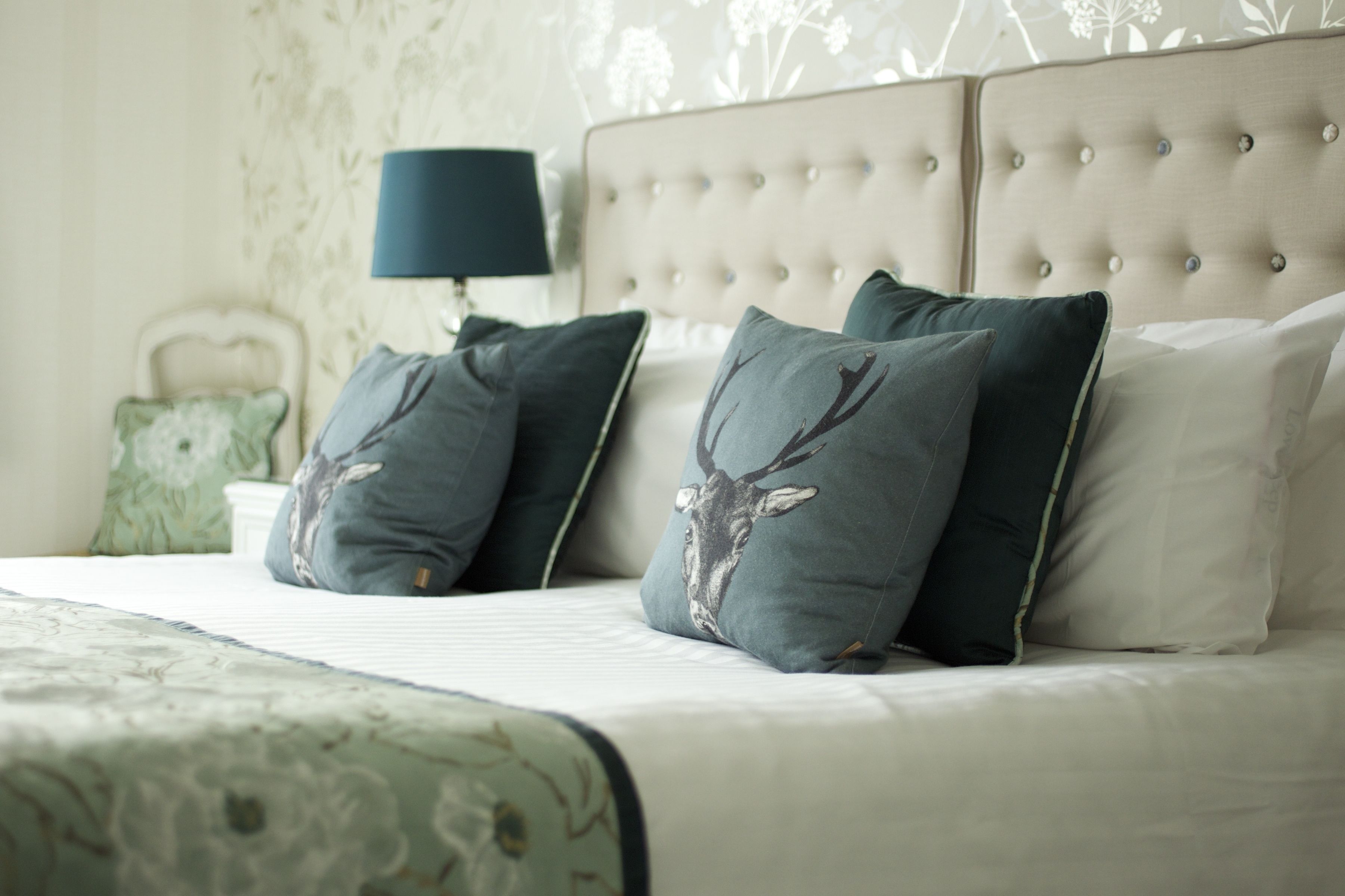 A neatly made bed with a patterned bedspread, a tufted headboard, and decorative pillows.