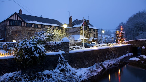 A historic building with a stone wall and a snow-covered garden. - Exmoor White Horse Inn (Minehead)