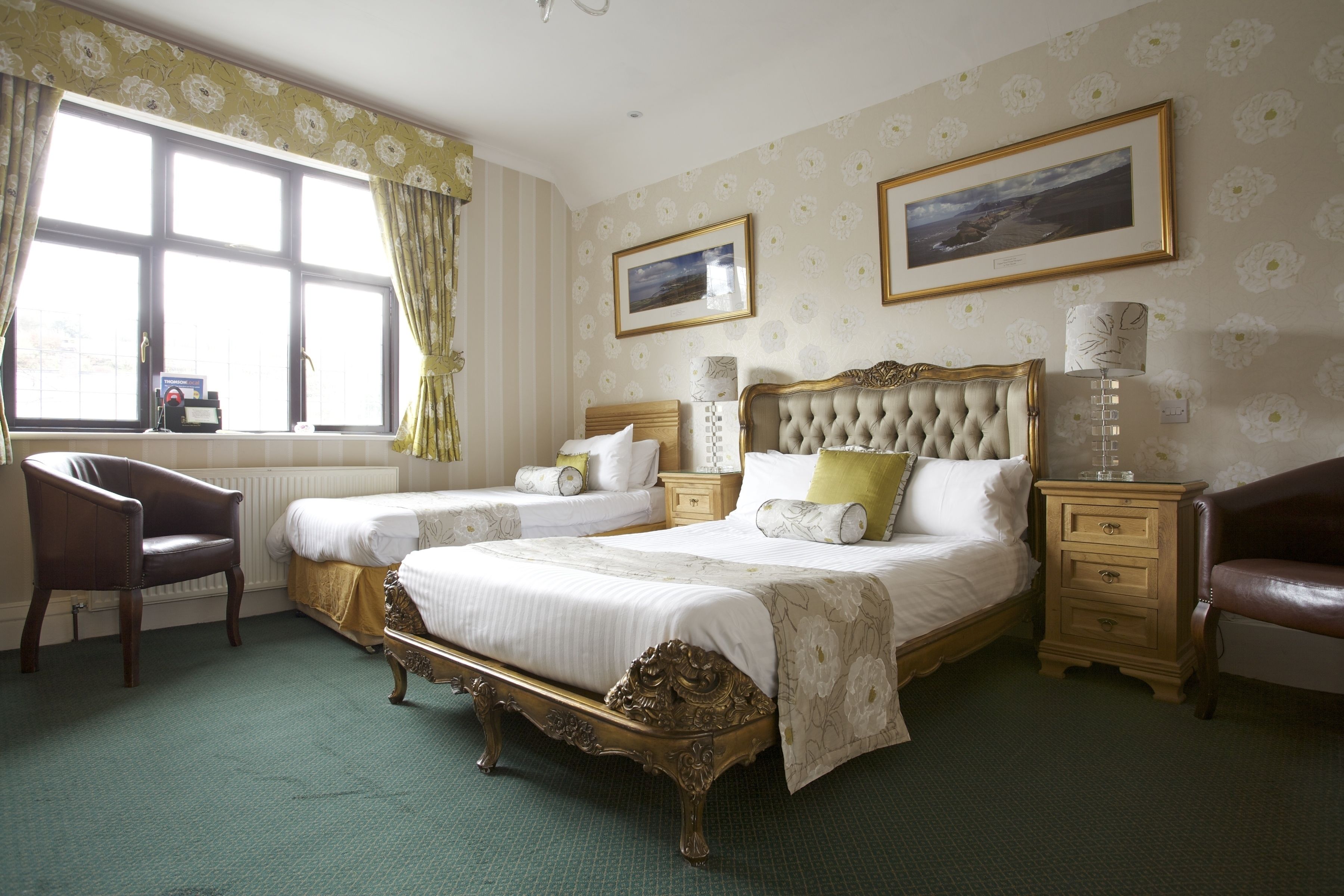A bedroom with two beds, a chair, a nightstand, and a window with curtains.