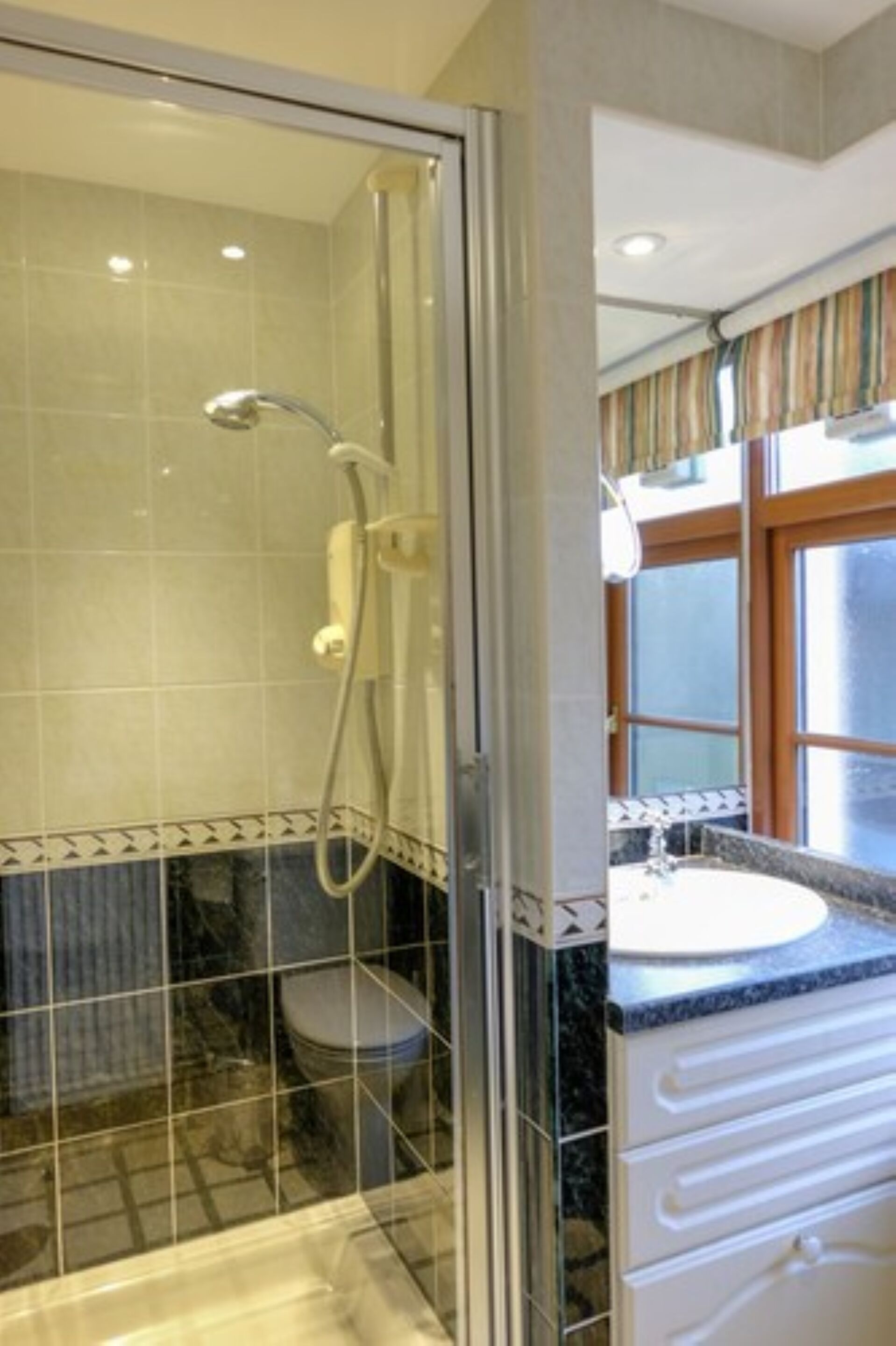 Un baño con ducha de vidrio, inodoro y lavamanos con encimera de mármol.