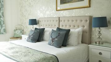 A neatly made bed with a floral bedspread, two bedside lamps, and a framed picture on the wall.