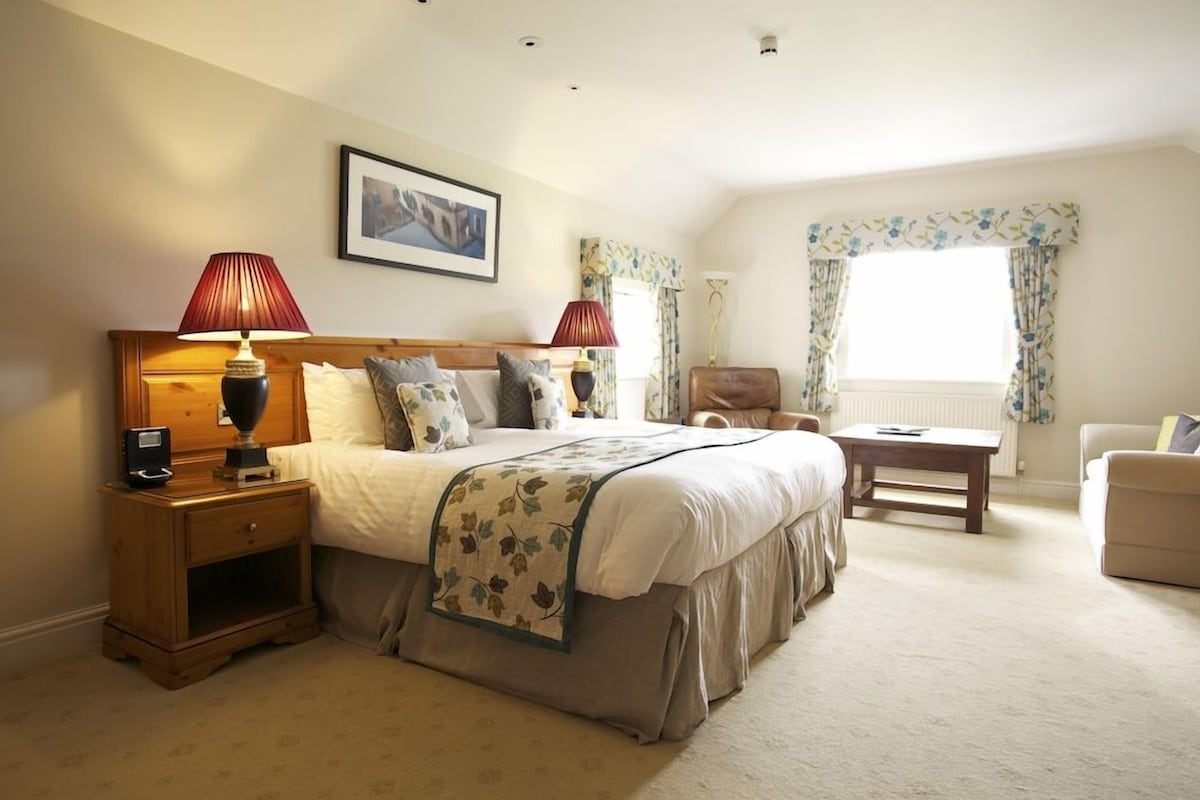 A bedroom with a bed, bedside tables, a desk, and a chair.