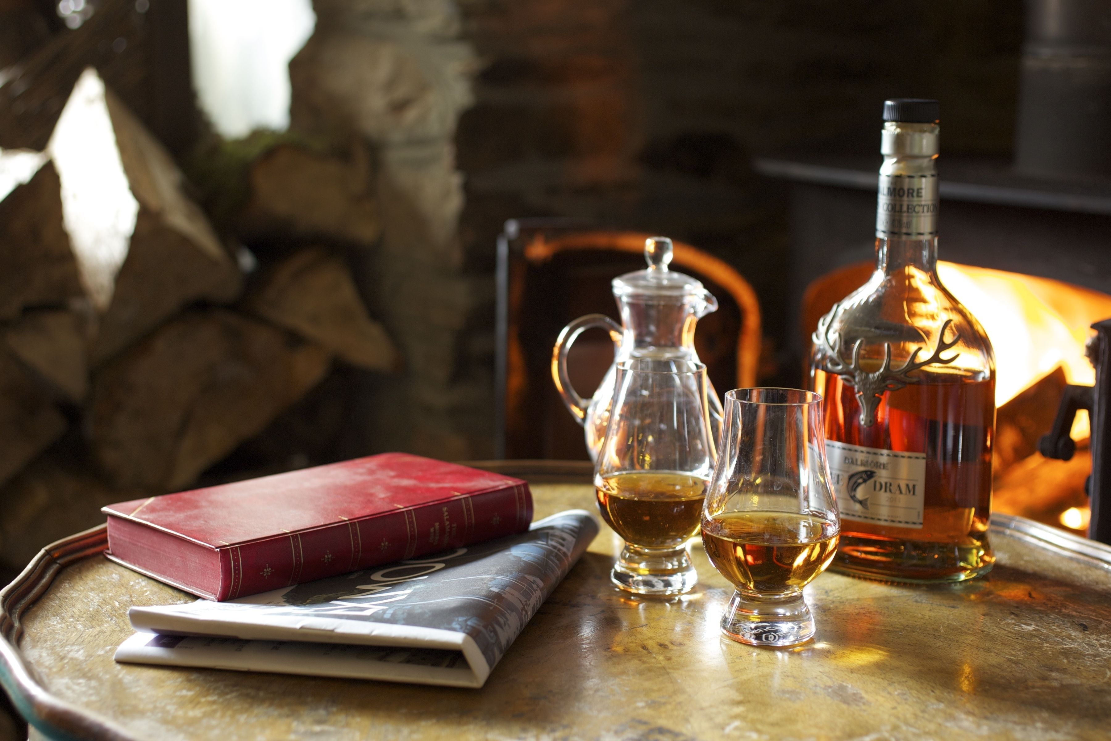 Una mesa con un libro, una jarra de vidrio, dos vasos y una botella.