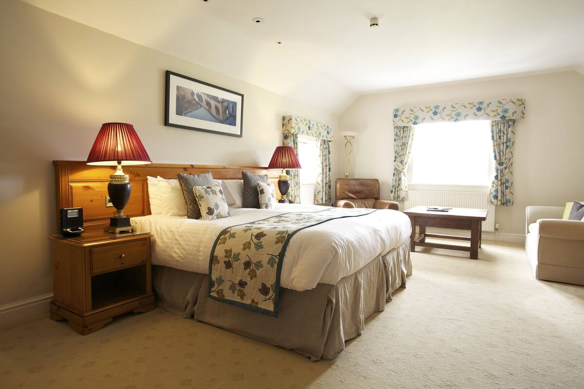 A neatly arranged bedroom with a large bed, bedside tables, a desk, and a chair.