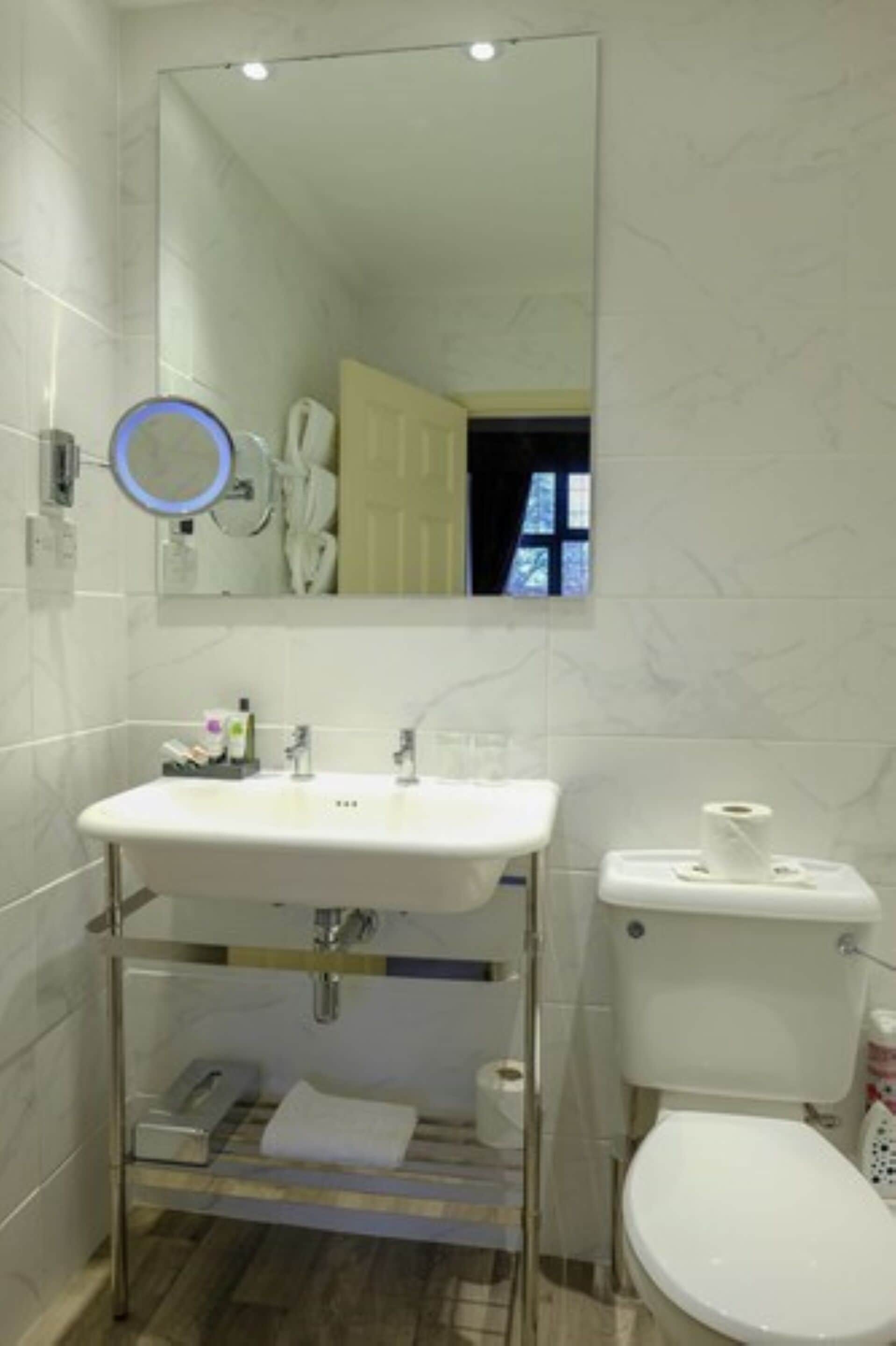 A bathroom with a white sink, mirror, and toilet.