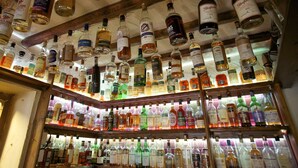 A bar with numerous bottles of liquor displayed on shelves and hanging from the ceiling. - Exmoor White Horse Inn (Minehead)