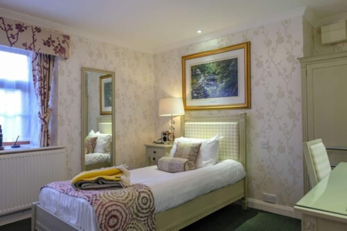 A bedroom with a bed, bedside table, lamp, and a framed picture on the wall.