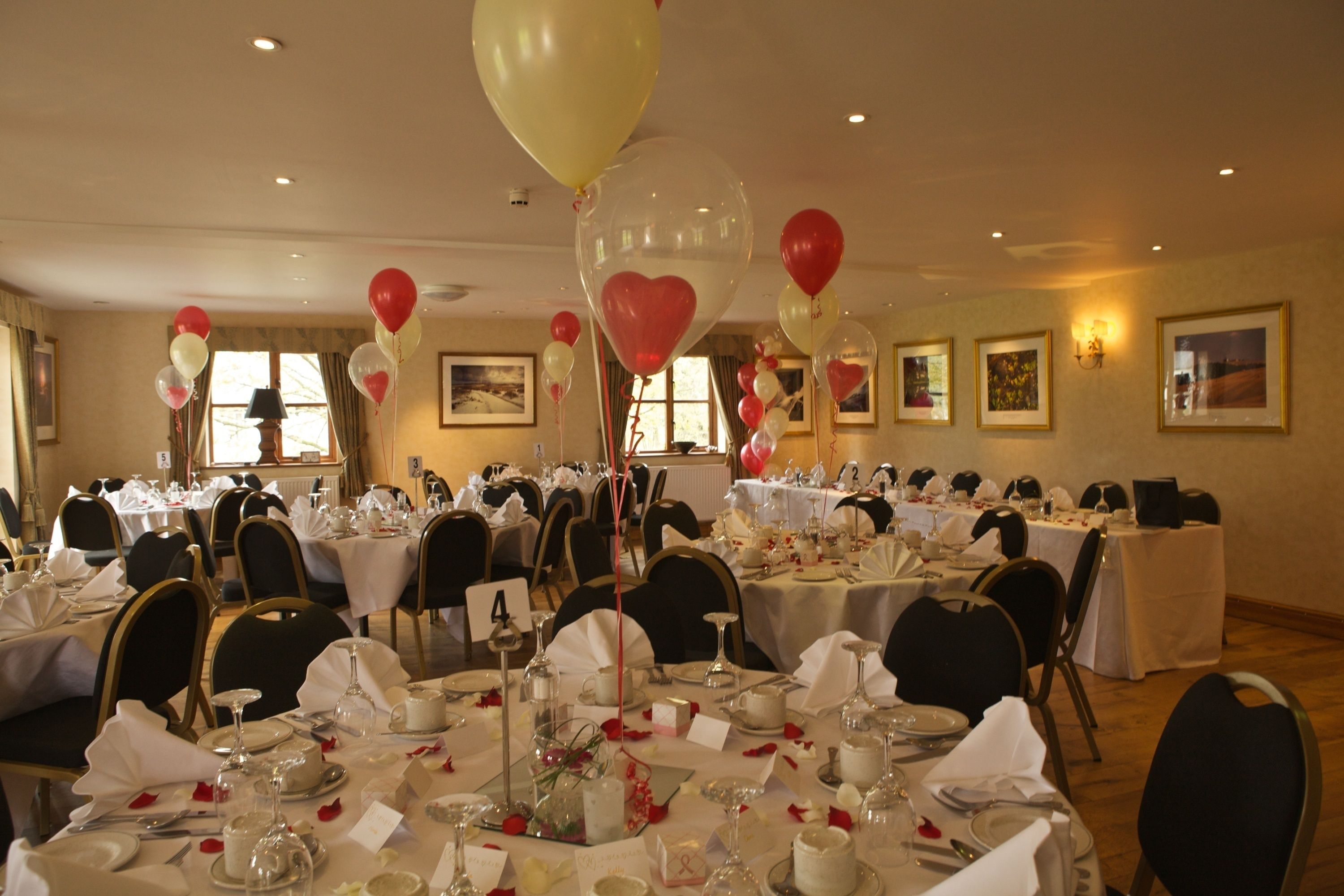 A banquet hall with round tables set for a formal event, featuring white tablecloths, glassware, and floral centerpieces.