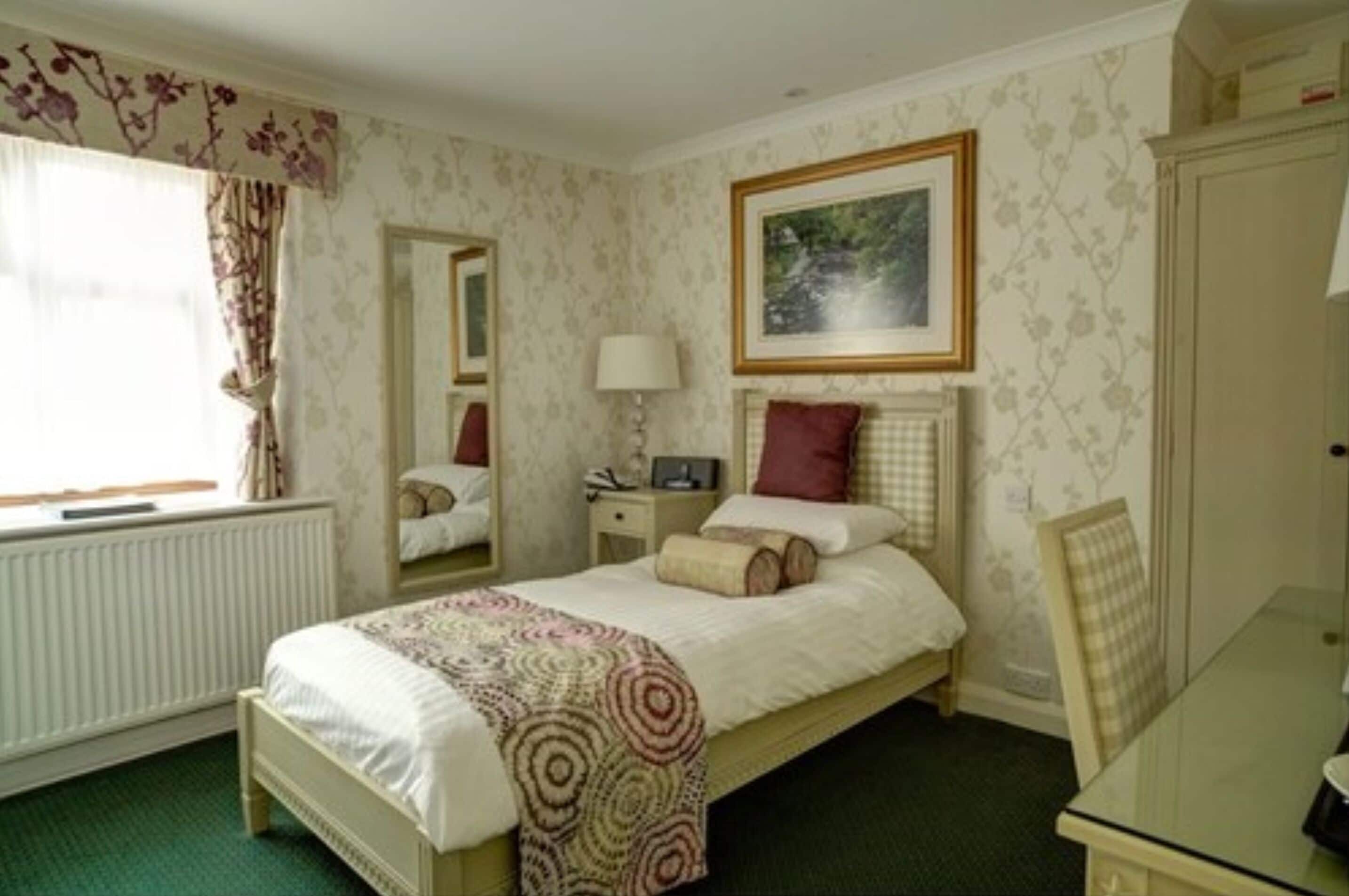 A bedroom with a bed, bedside table, lamp, and a painting on the wall.
