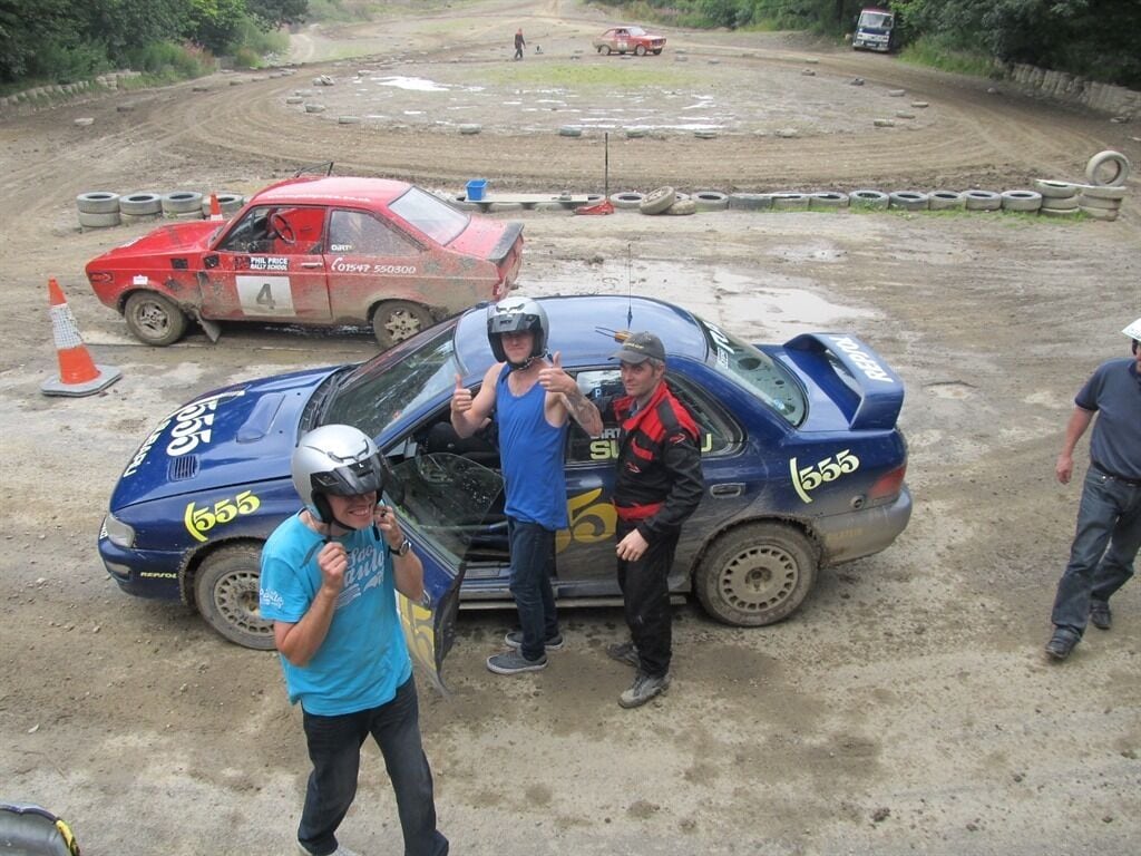 A rally car with the number 555 parked on a dirt track.