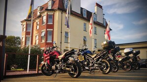 Motorräder sind vor einem Gebäude mit mehreren Flaggen abgestellt.