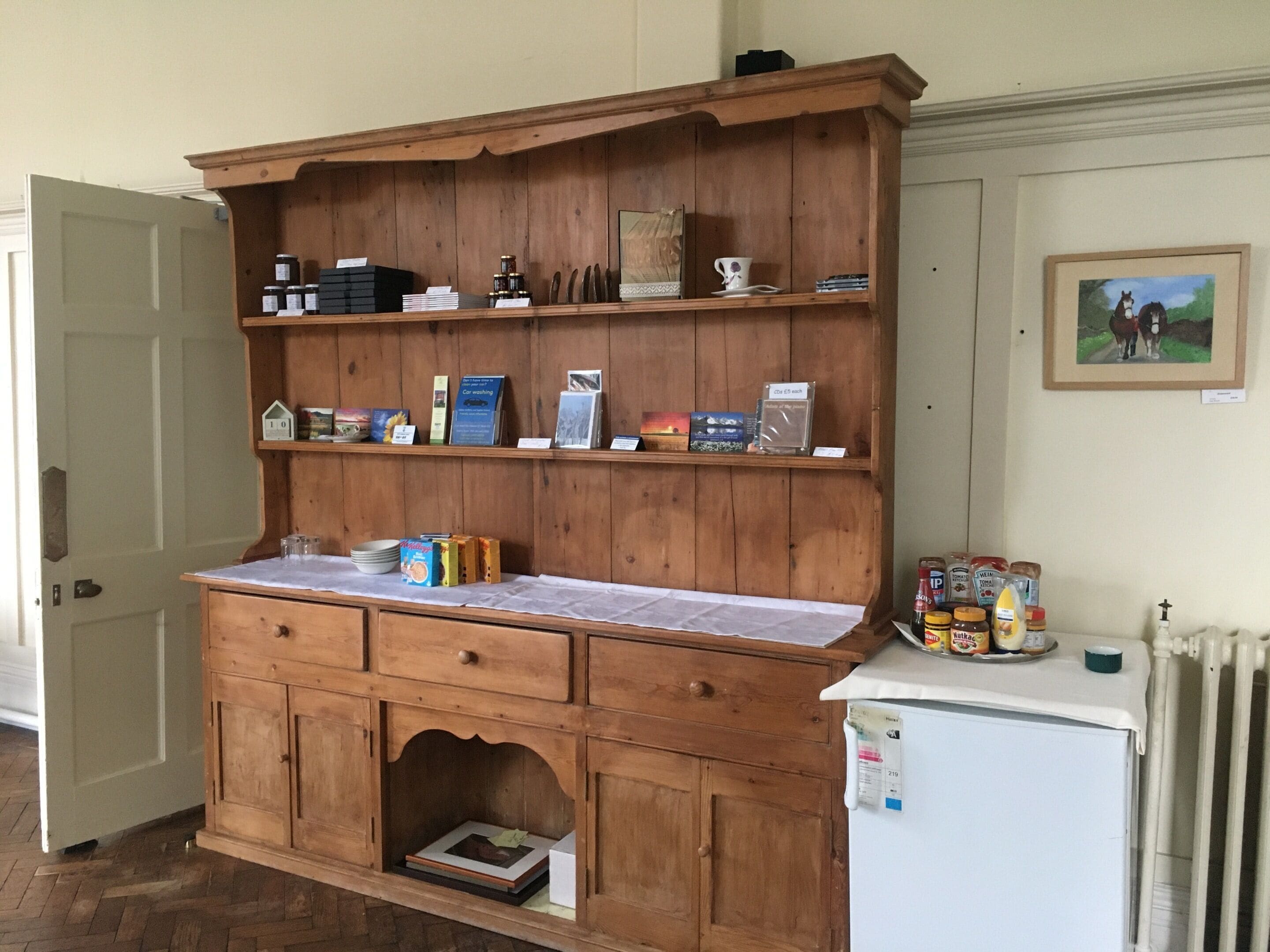 A wooden cabinet with multiple shelves, a countertop, and a small refrigerator.