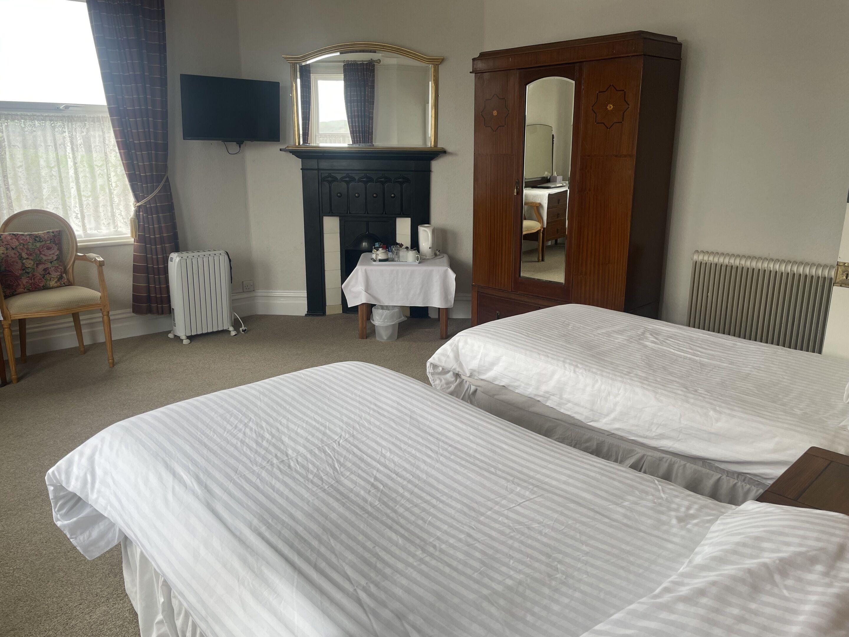 A bedroom with two beds, a dresser, a mirror, a table with a lamp, and a chair.