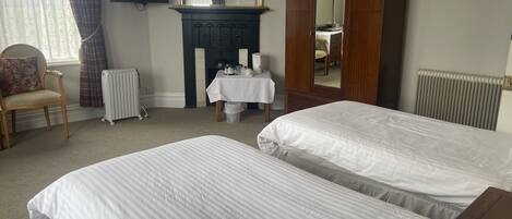 A bedroom with two beds, a dresser, a mirror, a table with a lamp, and a chair.