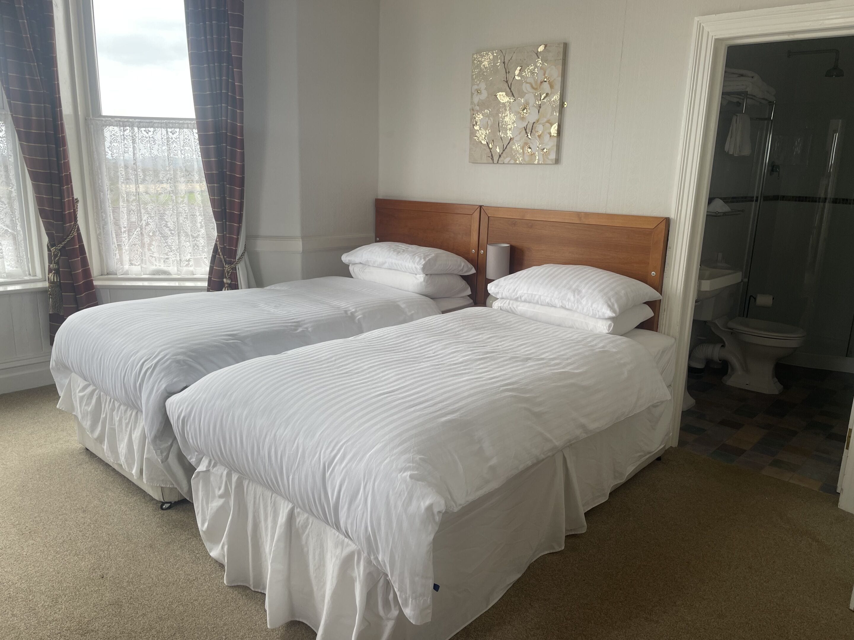 Una habitación de hotel con dos camas, ducha y baño.