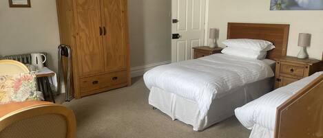 A bedroom with a bed, bedside tables, a wooden wardrobe, a chair, and a radiator.
