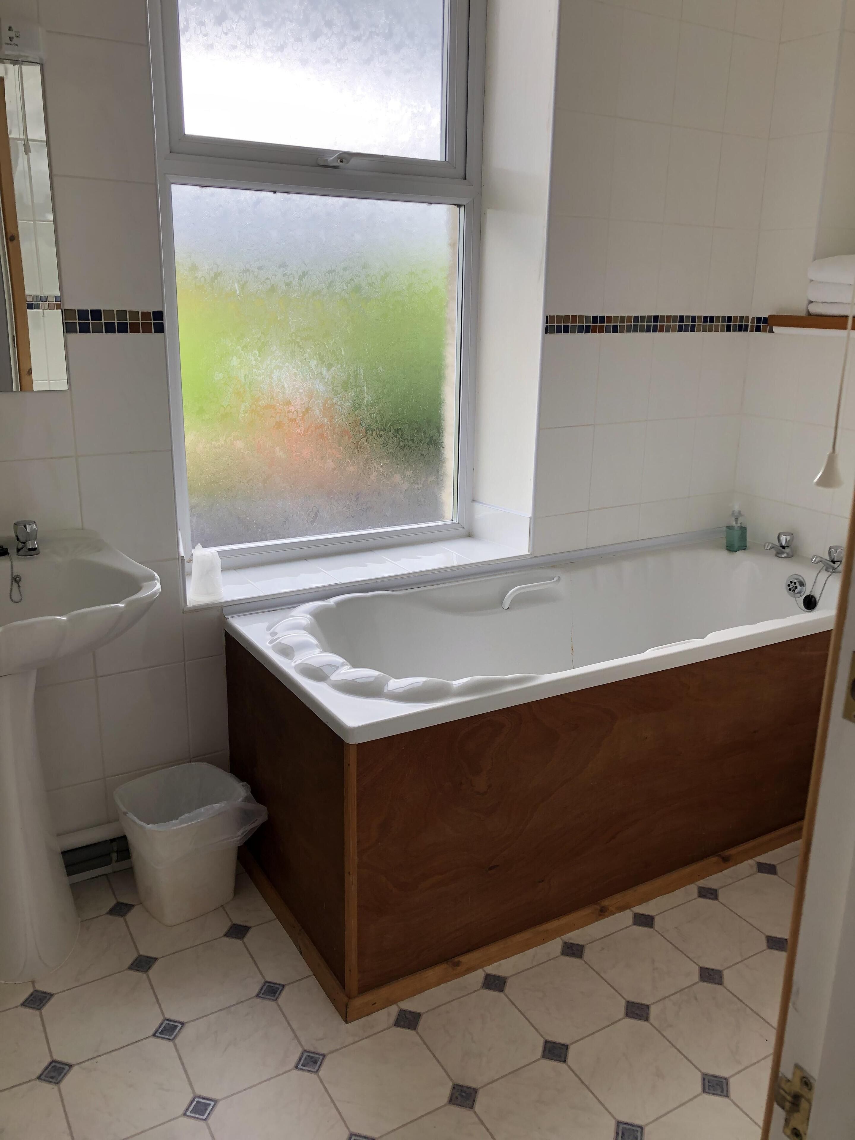 A bathroom with a bathtub, a sink, and a window.