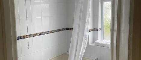 A bathroom with a bathtub, a window with a view, and a shower curtain.