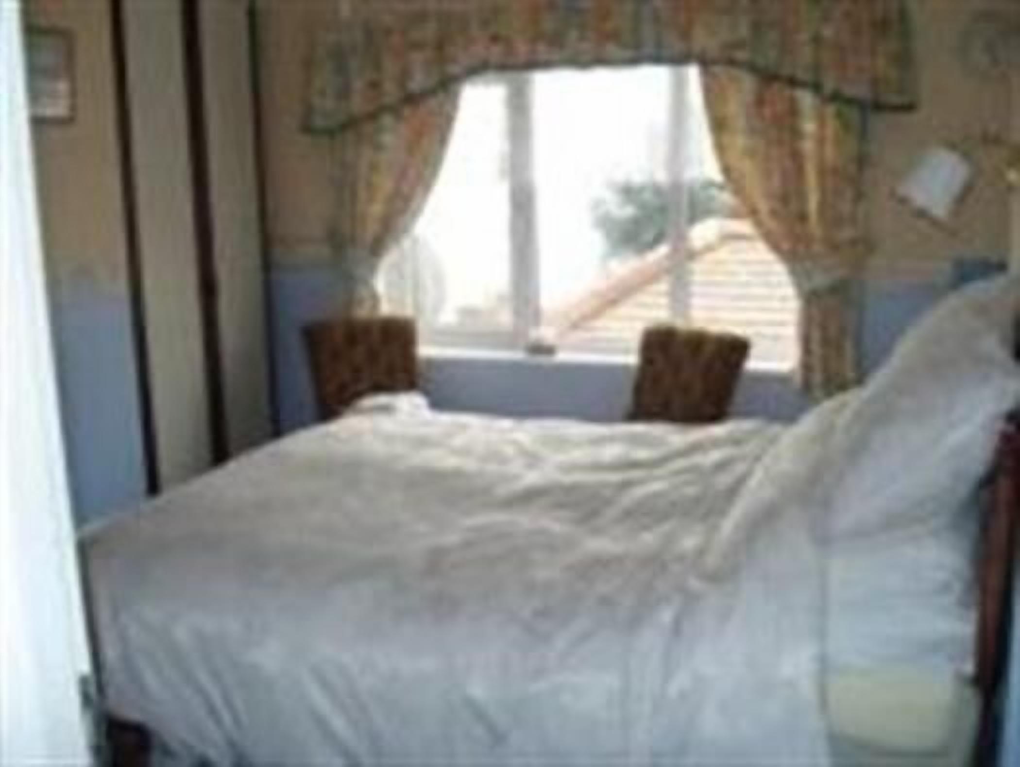 A bedroom with a bed, curtains, and a window.