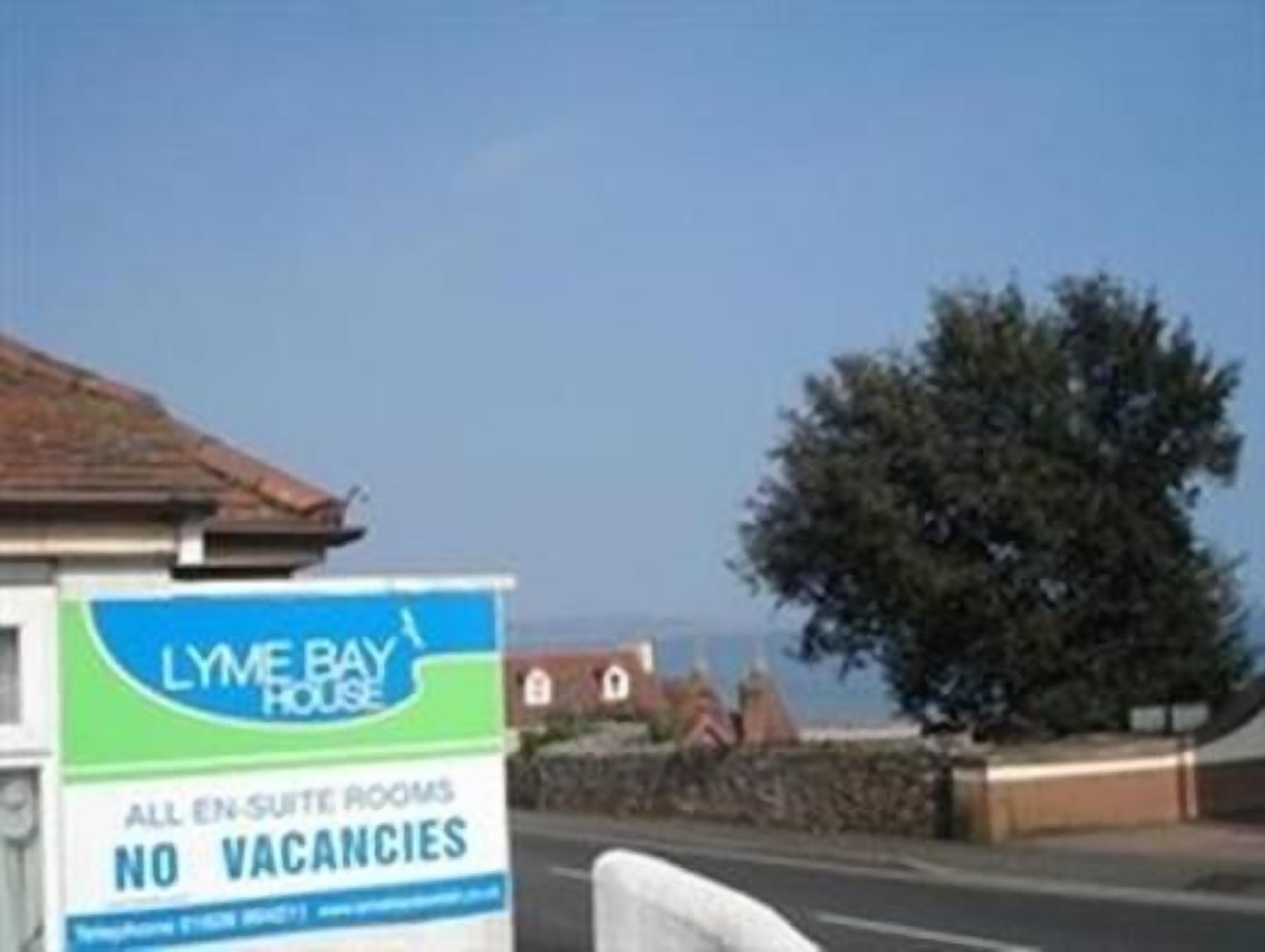 A sign for 'Lyme Bay House' advertising all en-suite rooms with no vacancies.