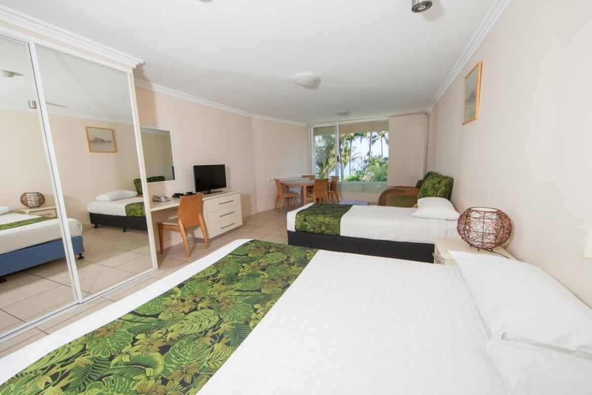 A hotel room with two beds, a desk, a chair, a television, and a large window.