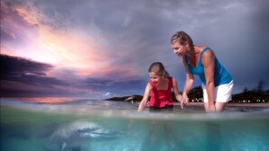 A woman and a child in a clear pool with a sunset in the background. - Tangalooma Island Resort (Moreton Island)