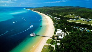 An aerial view of a coastal area with a beach, boats, and a pier. - Tangalooma Island Resort (Moreton Island)
