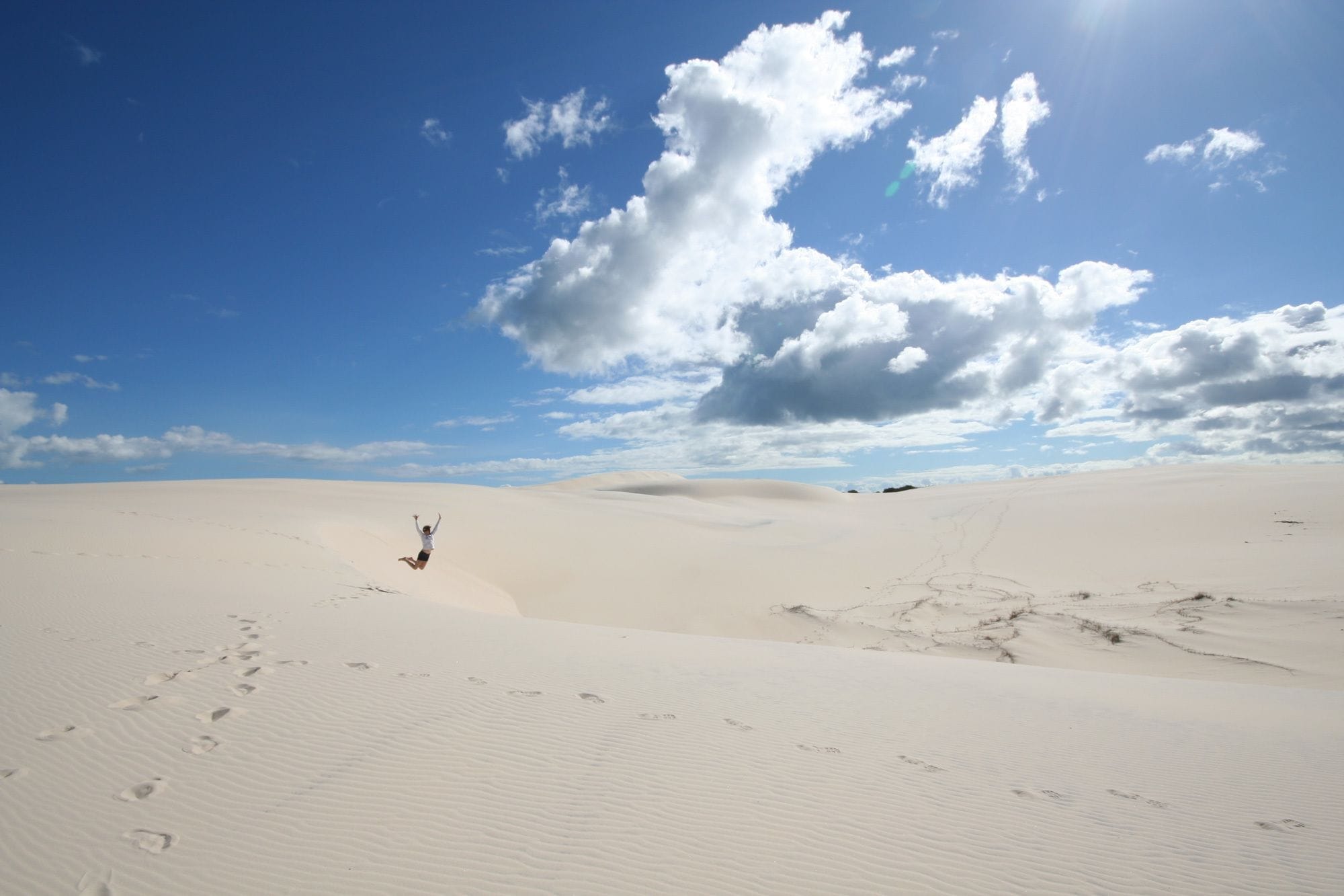 A vast desert landscape with sand dunes under a clear sky.
