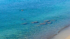 Une plage avec une eau cristalline et une personne qui nage.