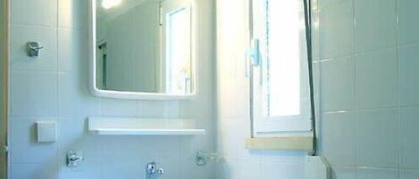 A bathroom with a white sink, a mirror, and a window.