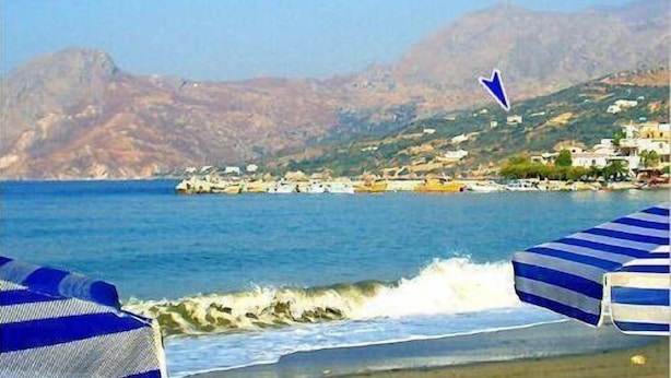 A coastal view with a rocky shoreline, a clear blue sea, and a mountainous backdrop. - Phoenix Apartments (Agios Vasileios)