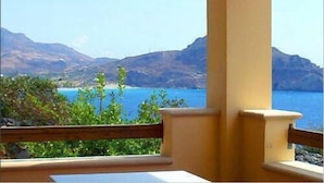 A balcony with a view of a coastal landscape, including a body of water and distant mountains. - Phoenix Apartments (Agios Vasileios)
