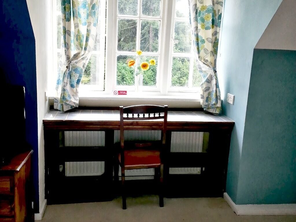 A room with a desk and chair, a window with curtains, and a radiator.