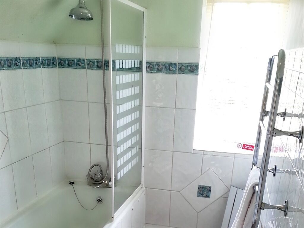 A bathroom with a shower, tiled walls, and a window.