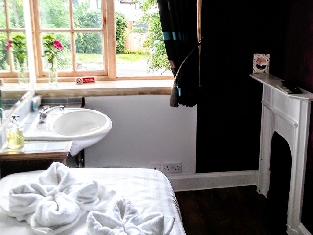 Un dormitorio con una cama, una ventana con cortinas, un lavabo y una chimenea.