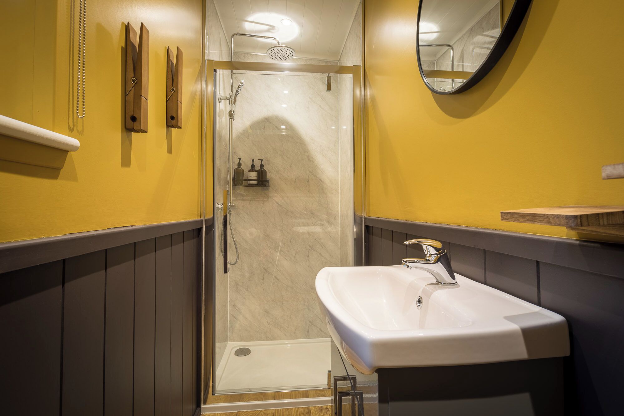 Un bagno con doccia vetrata, un lavandino bianco e uno specchio a parete.