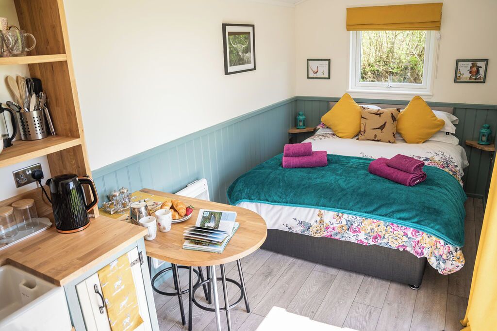 Een gezellig slaapkamer met een bed, een nachtkastje, een raam en uitzicht op groen.