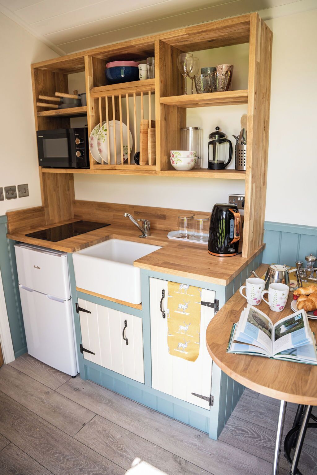 A compact kitchen with a double sink, a microwave, a coffee maker, and a small refrigerator.