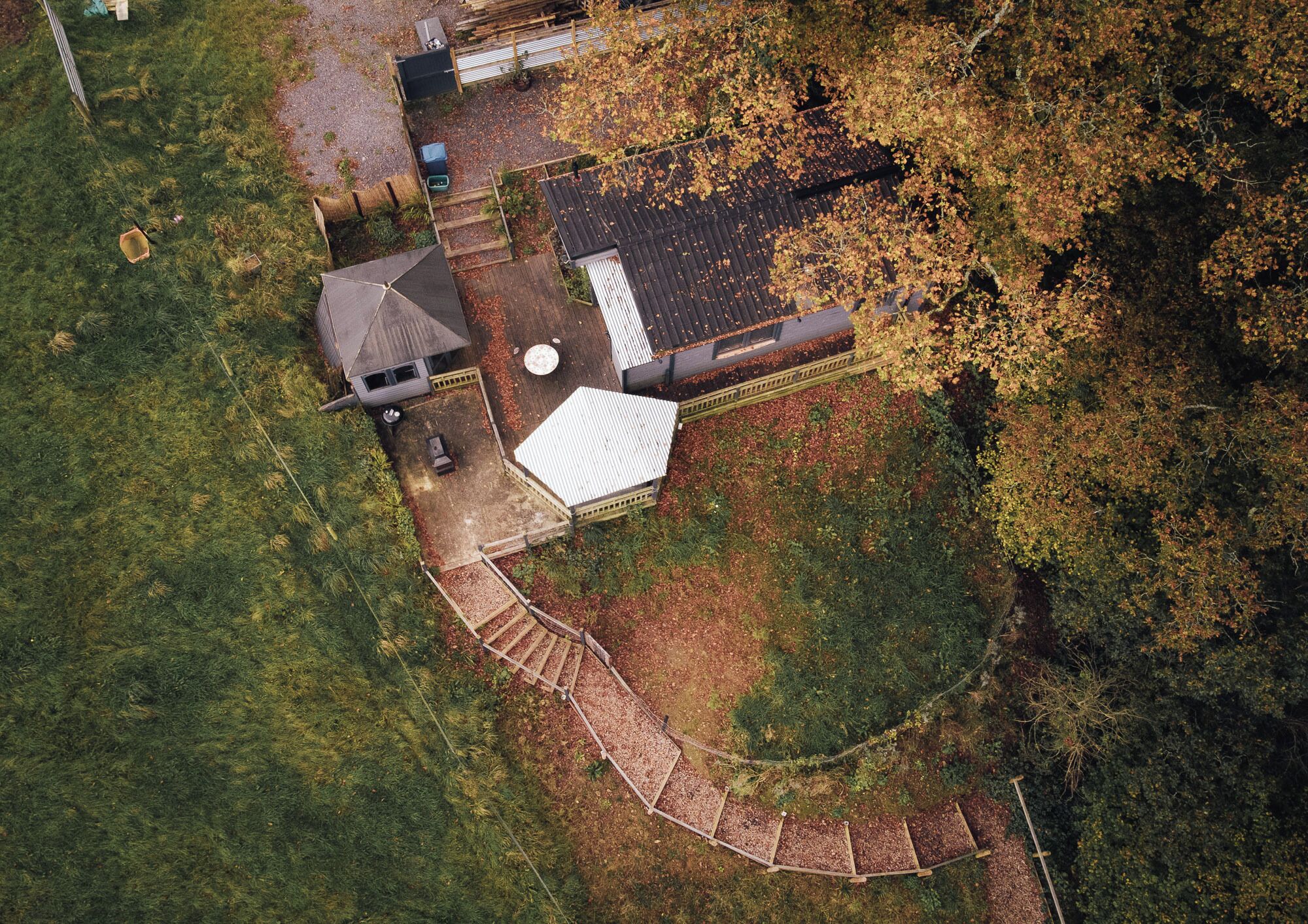 An aerial view of a property with a fenced yard, a small building with a sloped roof, and a circular structure.