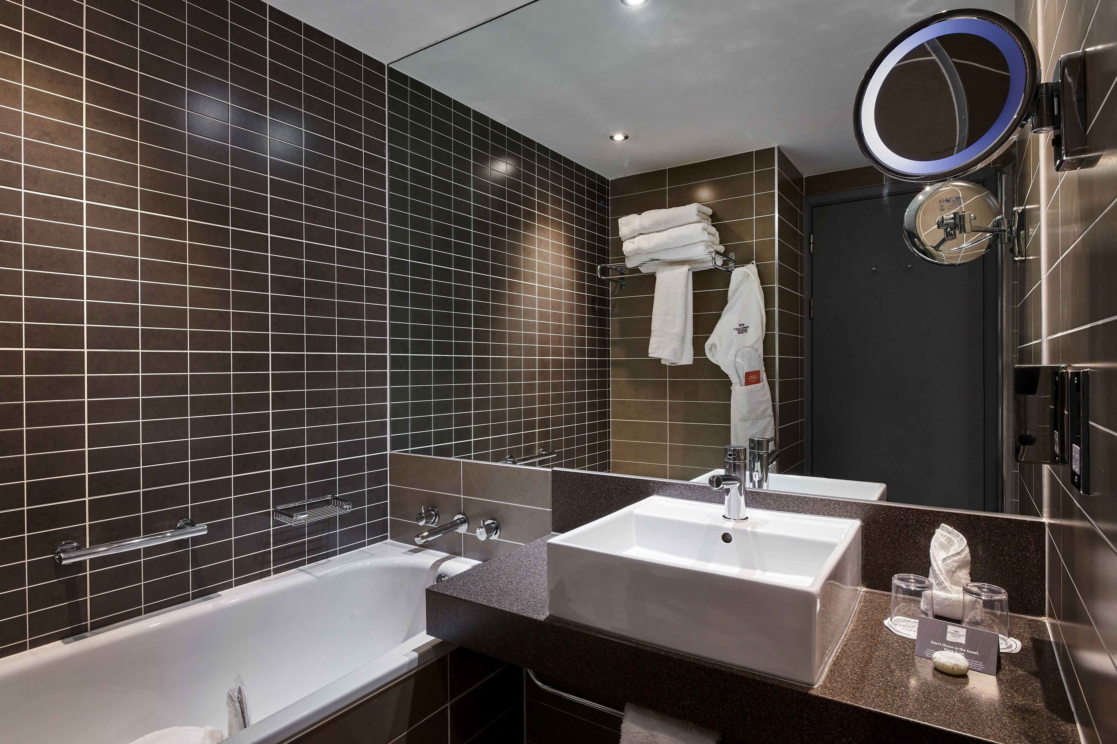 A modern bathroom with two sinks, a bathtub, and a large mirror.
