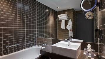 A modern bathroom with two sinks, a bathtub, and a large mirror.