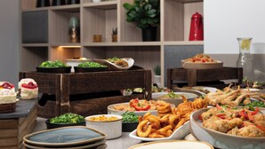Ein Buffet mit verschiedenen Speisen, Holzmöbeln und Pflanzenregalen.