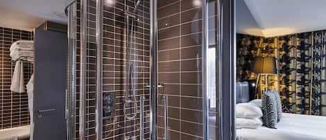 A modern bathroom with a glass-enclosed shower, a bathtub, and a vanity with a towel rack.