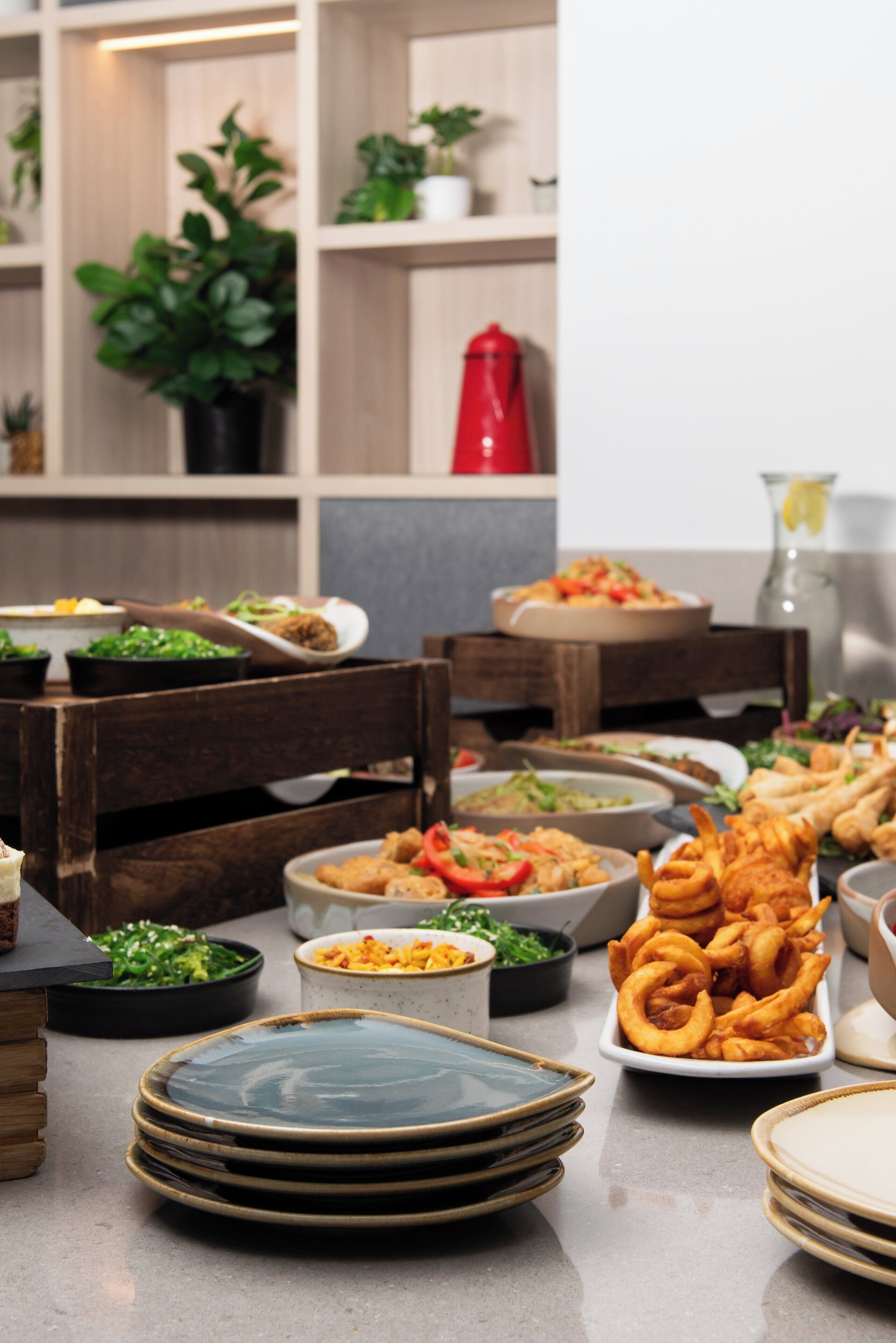 A buffet table with various dishes and plates.