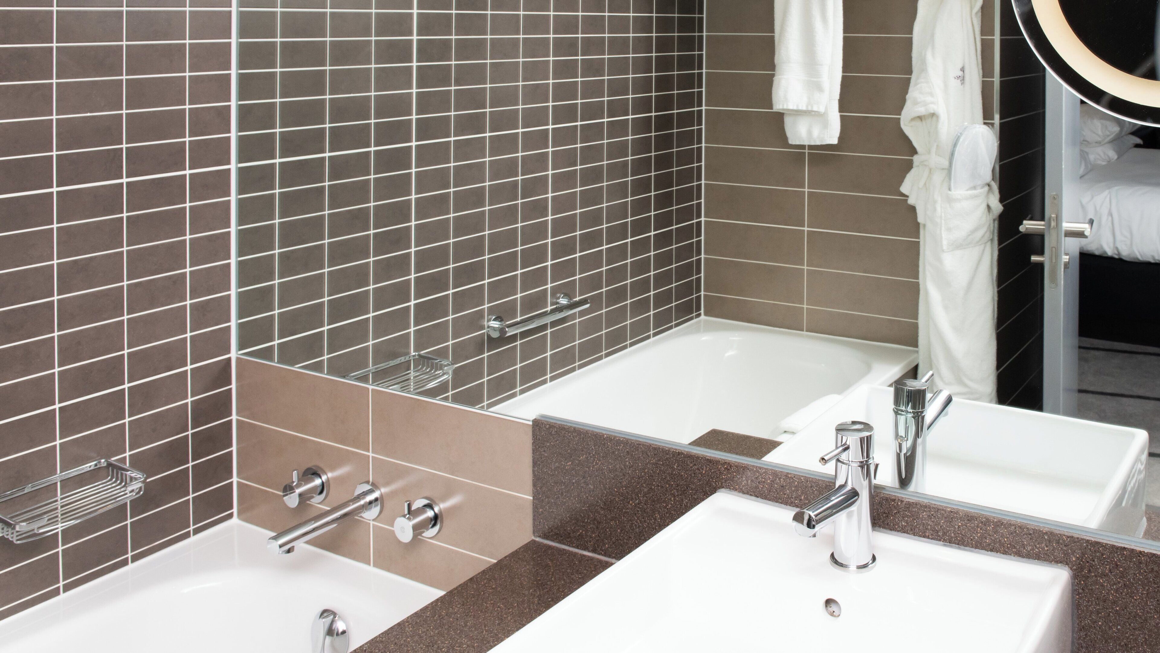 A bathroom with two sinks, a mirror, and a towel rack.