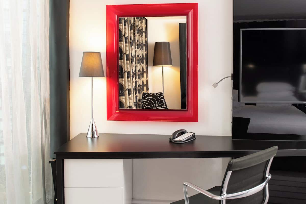 Een hotelkamer met een bureau, een stoel, een telefoon, een lamp en een bed.