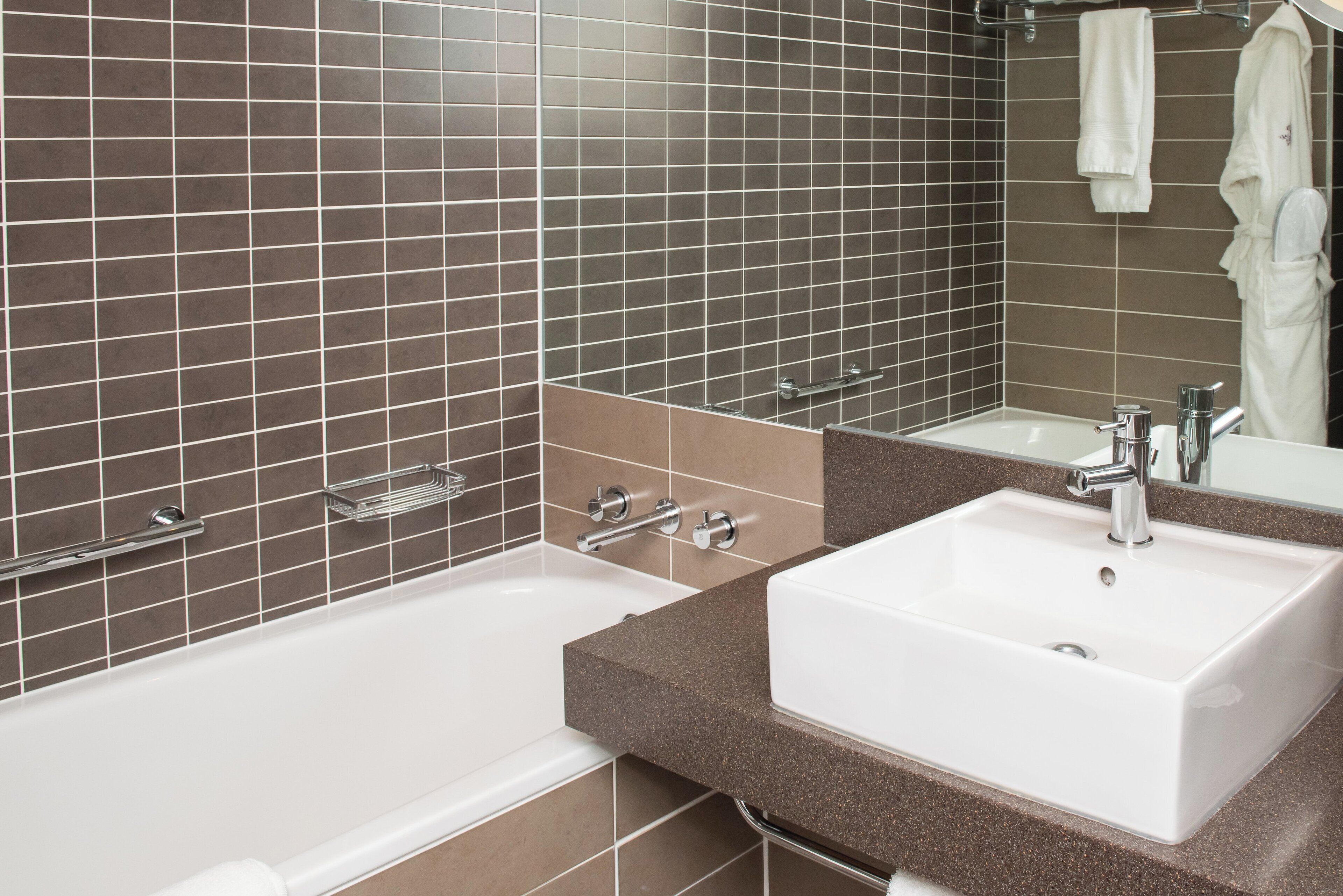 A modern bathroom with two sinks, a bathtub, and a large mirror.