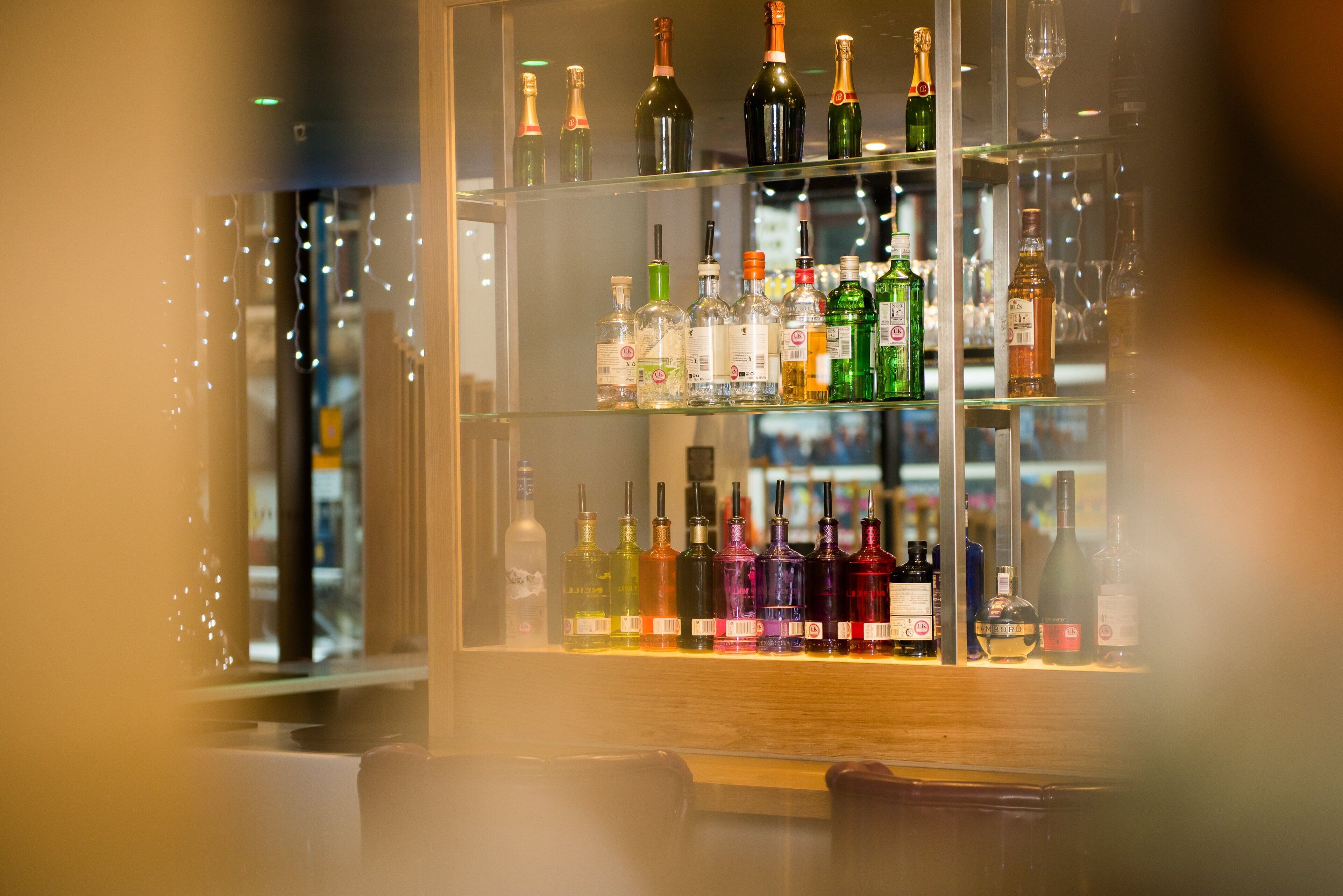 Un bar con estantes llenos de botellas de licores y vasos.